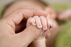 pasgeboren-baby-die-zijn-oudershand-houdt-10431941