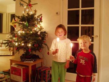 kinderen bij kerstboom met brandende kaarsjes