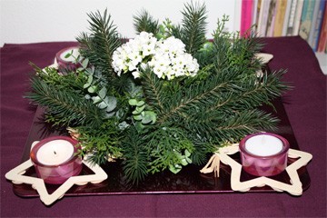 adventskijktafel met vier houten sterren en paarse waxinelichtjes op paars onderbord