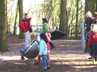 kinderen-in-speeltuin-man-met-kindje-in-draagzak