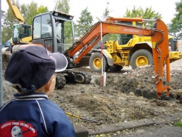 jongentje bij bouwplaats, buldozer en graafmachine