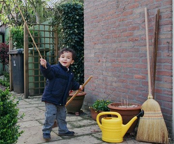 kind met bezem in voorjaarstuin